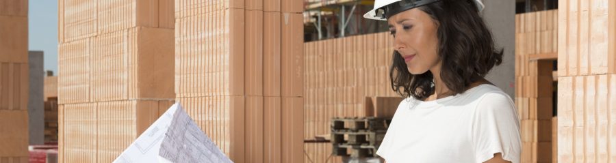 Female architect looking at technical drawing at construction site