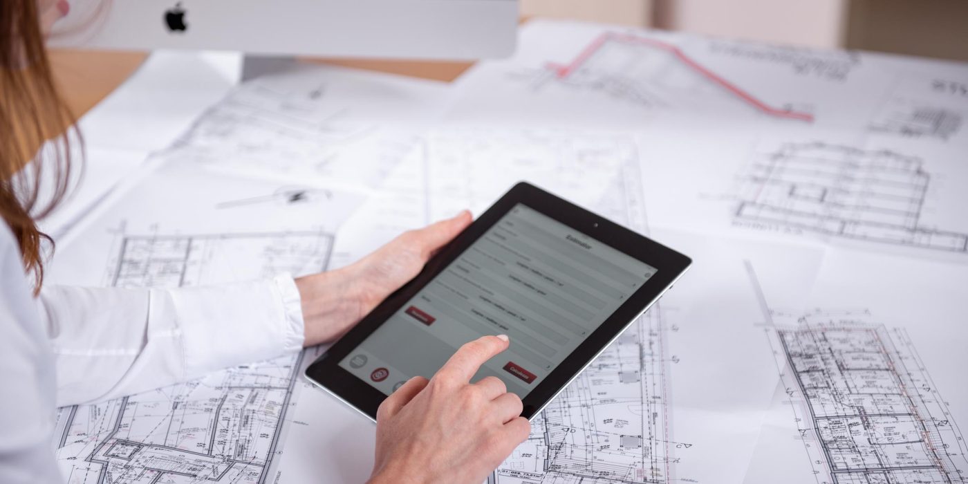 Woman at workplace with blueprint holding tablet computer