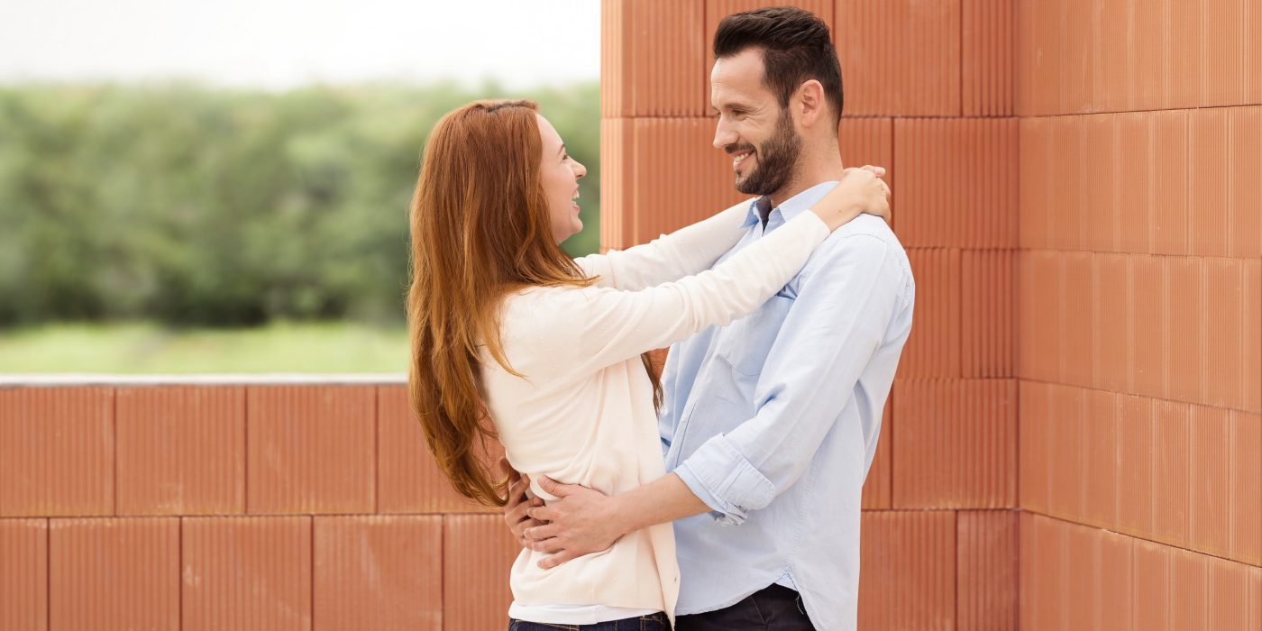 Man and woman celebrating their future home inside building shell