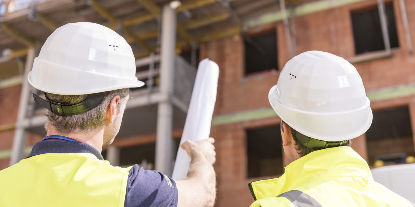 Builder pointing at building shell with blueprint