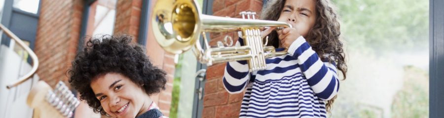 Noisy kids playing electrical guitar and trumpet inside well insulated brick-built house