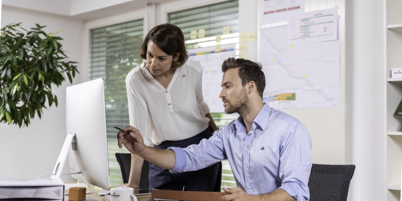 Male and female project manager collaborating in front of computer screen at office