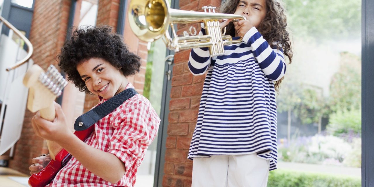 Noisy kids playing electrical guitar and trumpet inside well insulated brick-built house