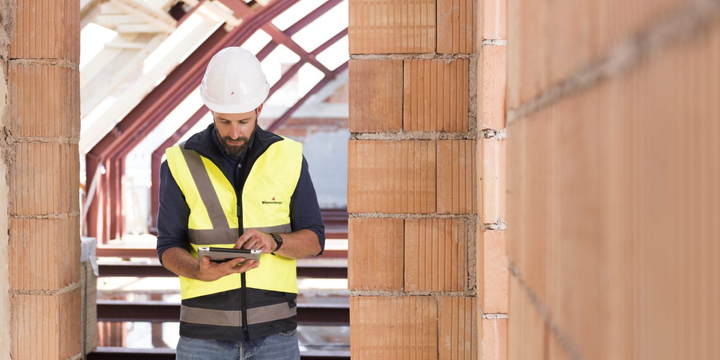 Product manager standing in attic under renovation checking tablet