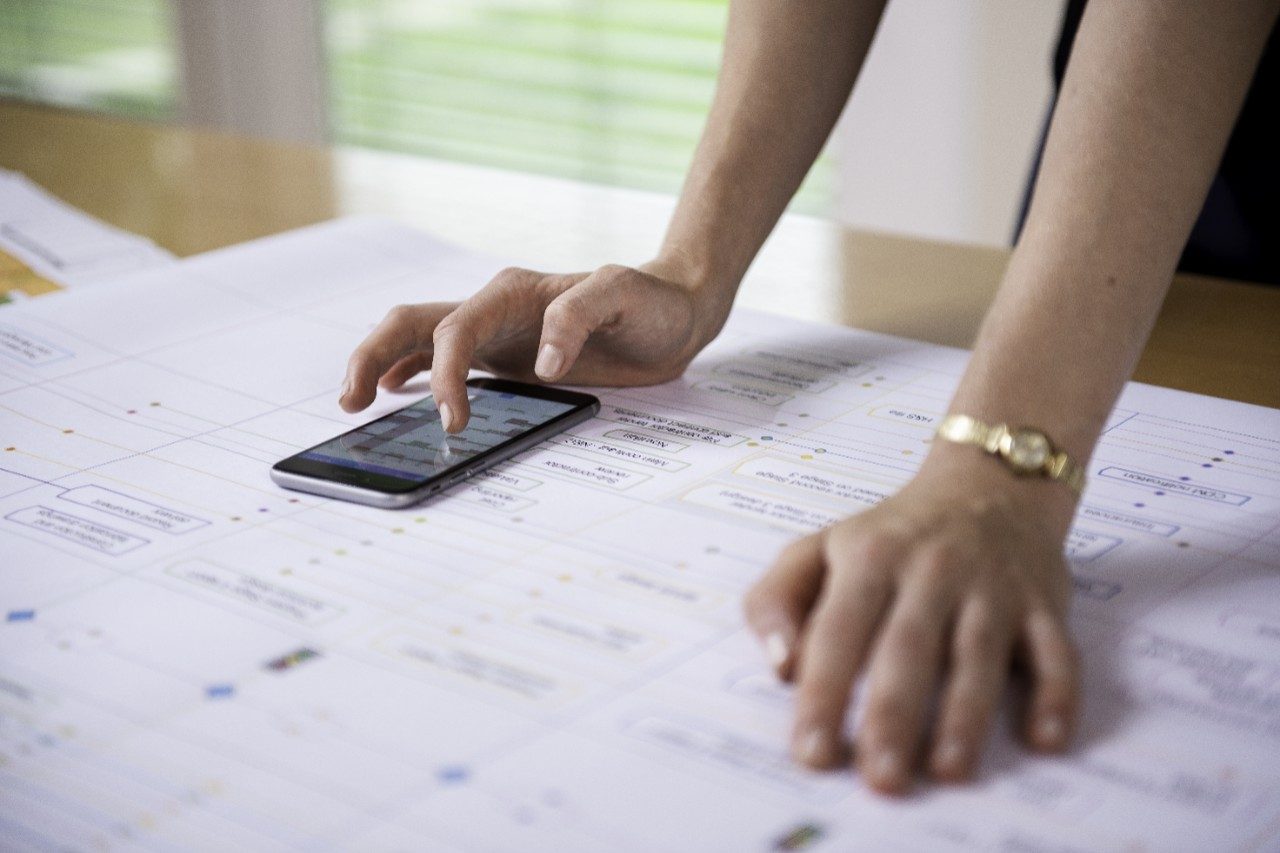 Project manager aligning project process map with calendar app on mobile phone