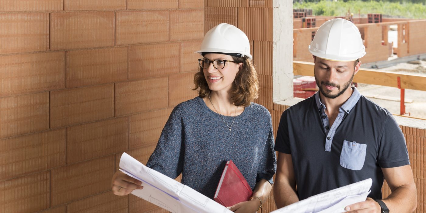 Male and female building professionals with technical drawing in new built construction