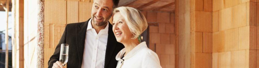 Couple inside building shell surrounded by bare brickwork celebrating their new home