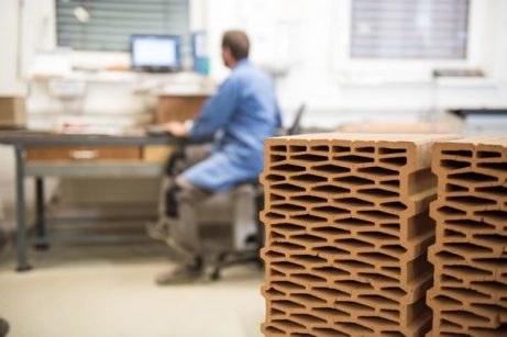 Worker in laboratory with clay blocks in foreground