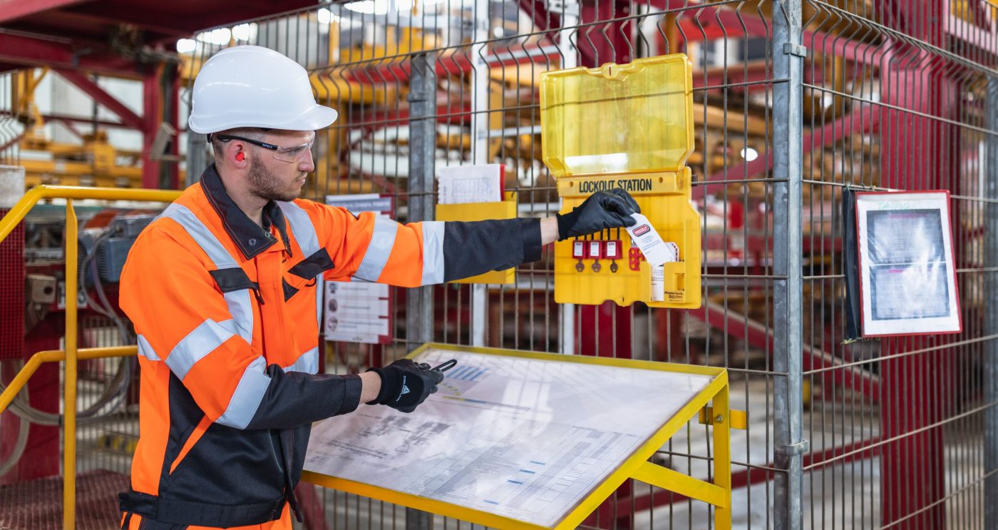 Factory worker locking out machine with LOTOTO safety hasp