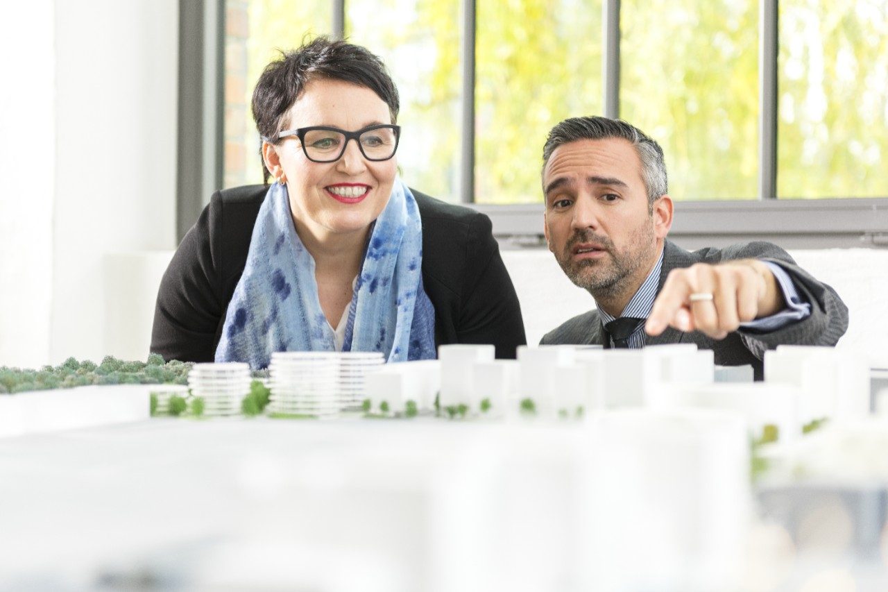 Man and woman talking about a new building project pointing at an architectural model