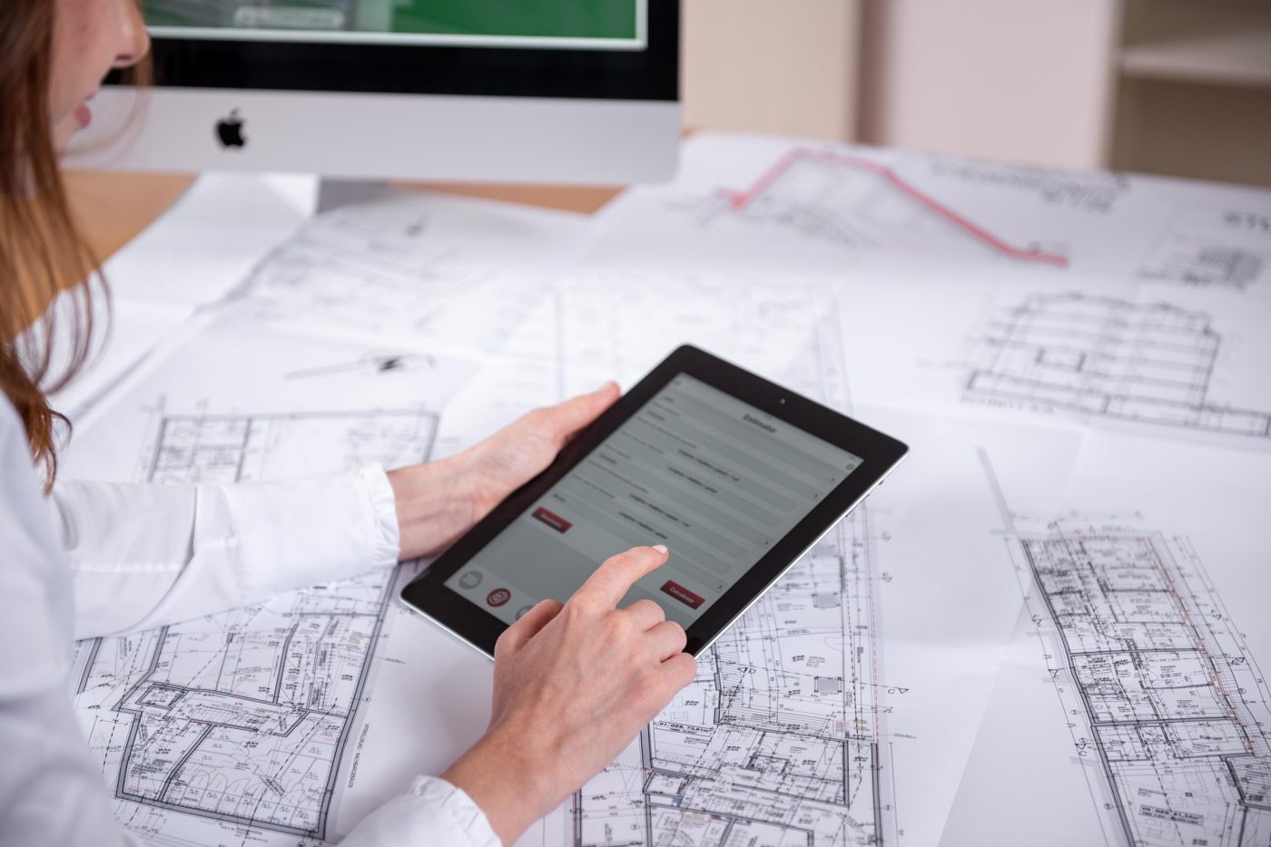 Woman at workplace with blueprint holding tablet computer