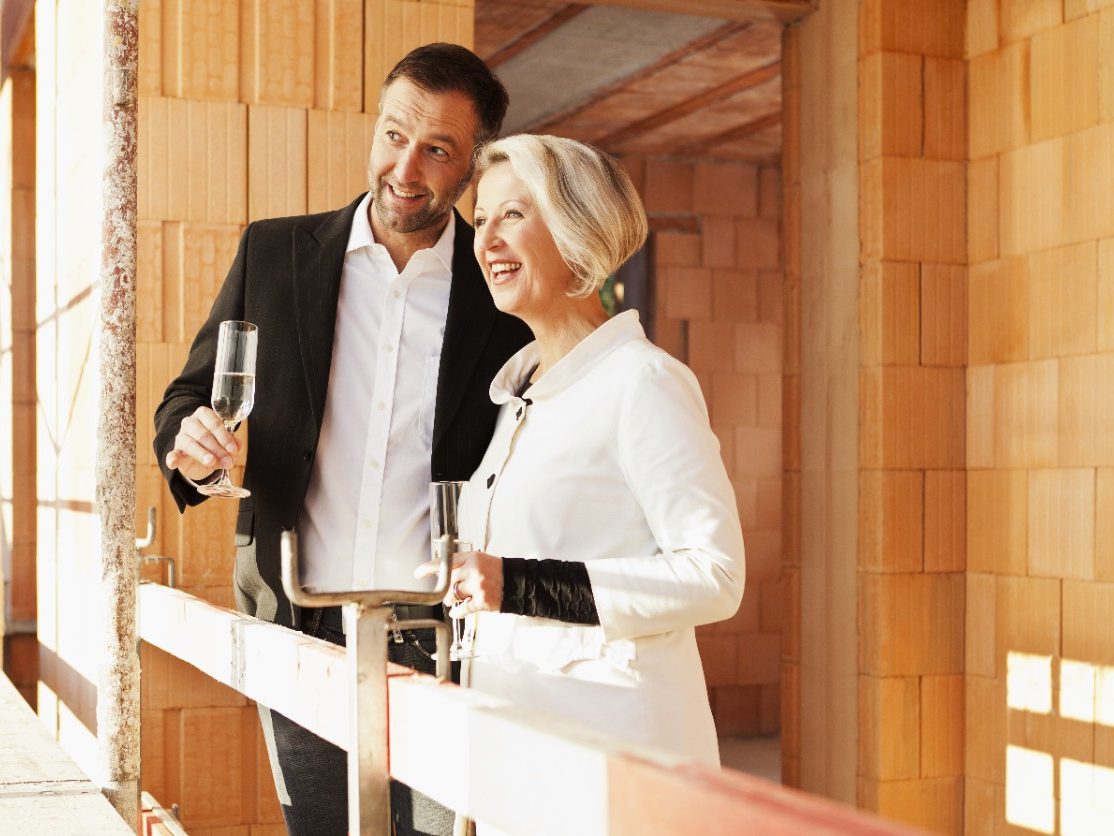 Couple inside building shell surrounded by bare brickwork celebrating their new home