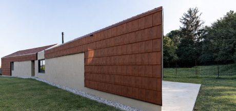 Prospetto laterale della casa con involucro continuo in cotto e volume compatto