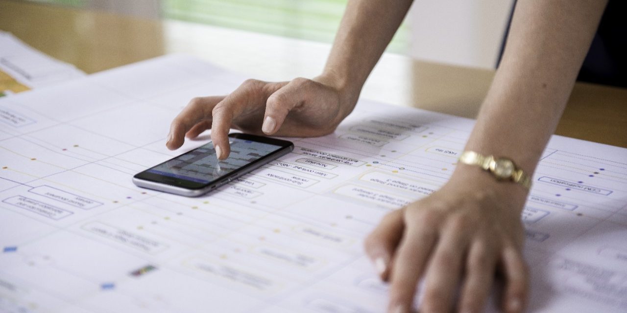 Project manager aligning project process map with calendar app on mobile phone