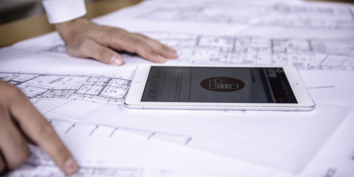 Tablet computer and hands at blueprint