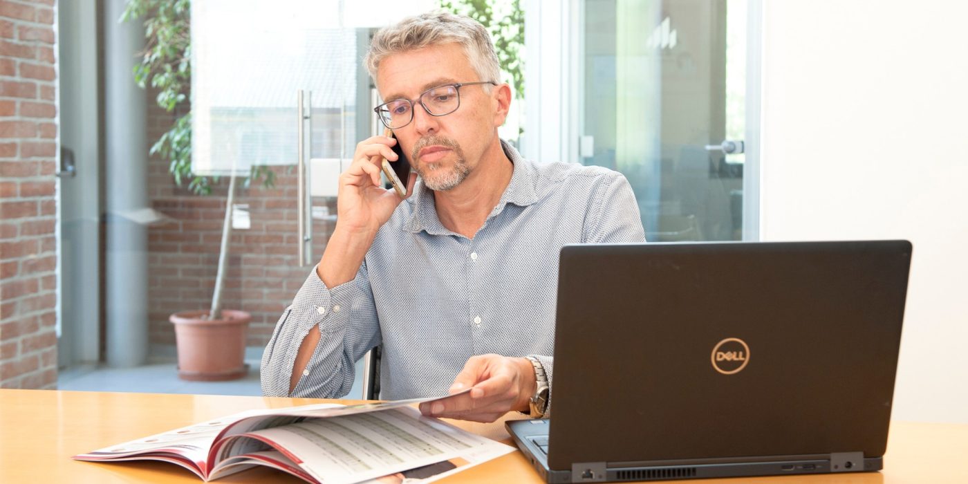 Progettista al telefono con catalogo e pc